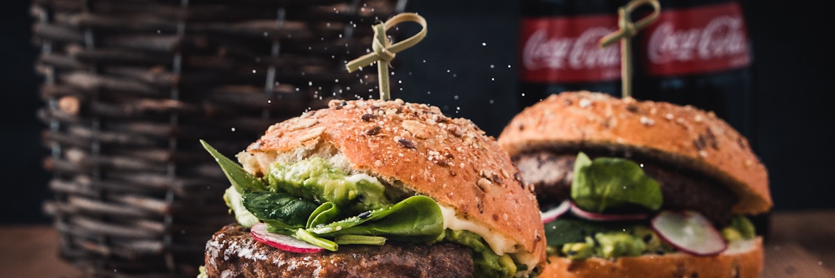 A sizzling smash burger being pressed on a flat-top grill with steam rising in dramatic golden light